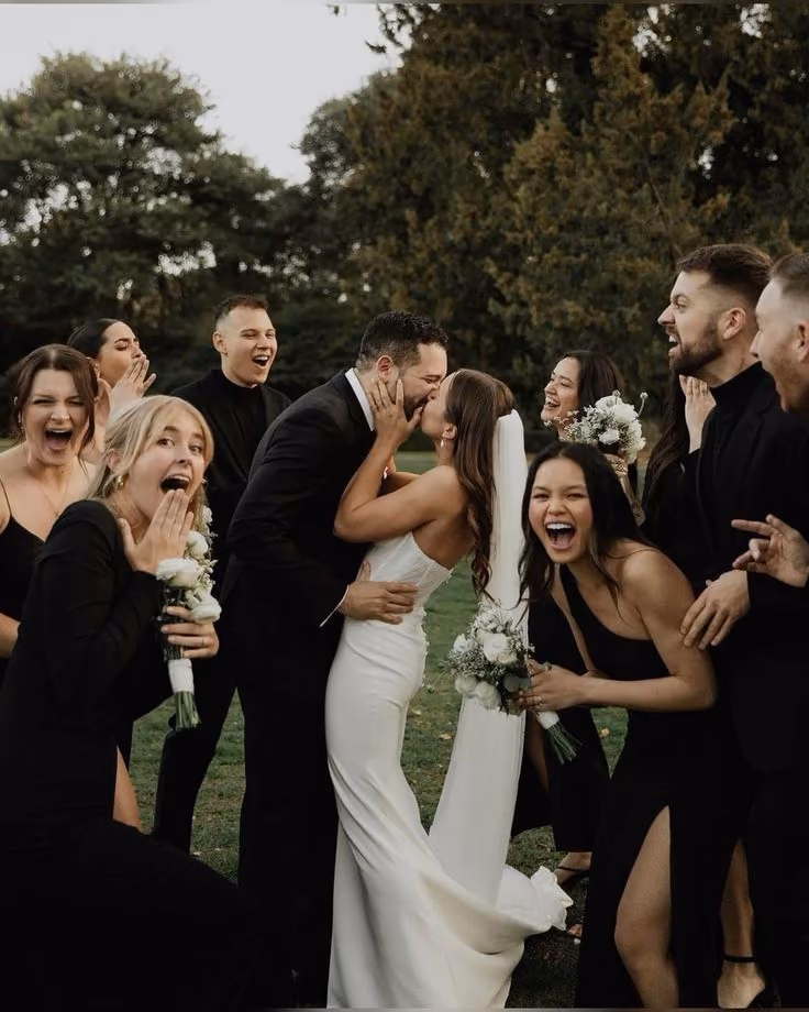 Bride and groom kissing while the wedding party cheers