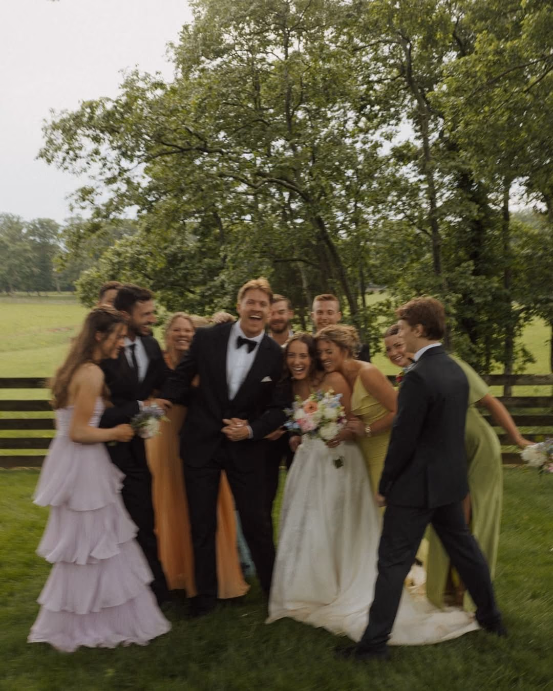 Bride, groom, and wedding party laughing outdoors