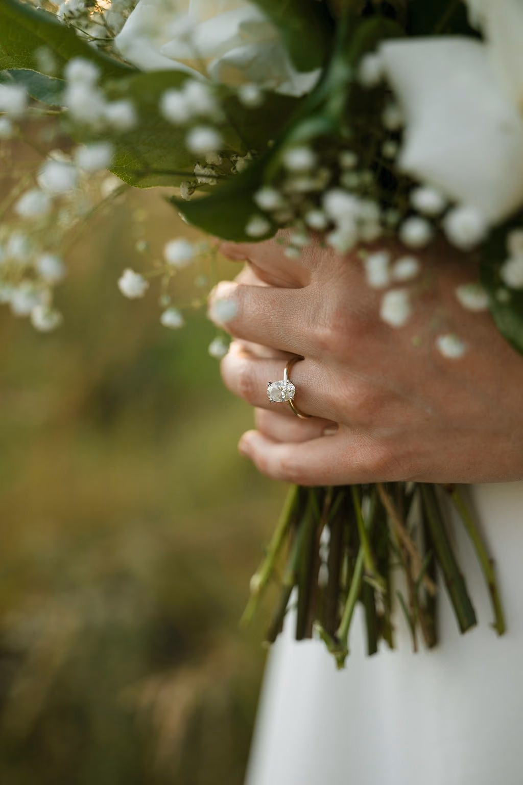 Hand with an engagement ring holding a bridal bouquet
