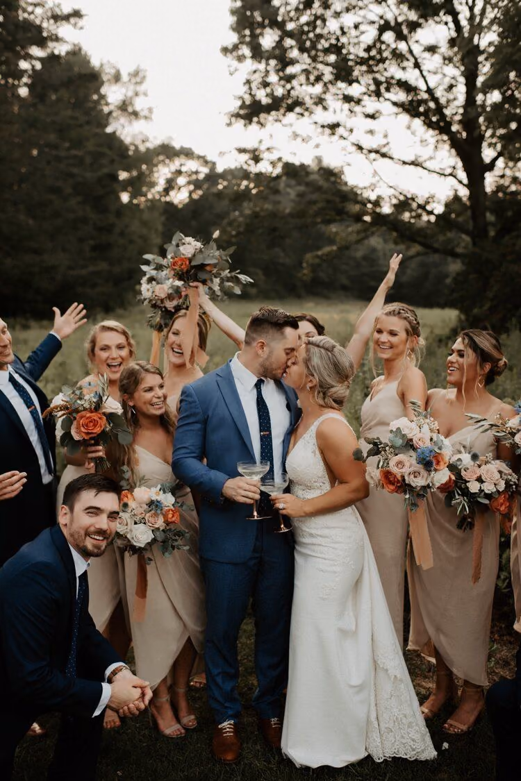 Bride and groom kissing while the wedding party cheers