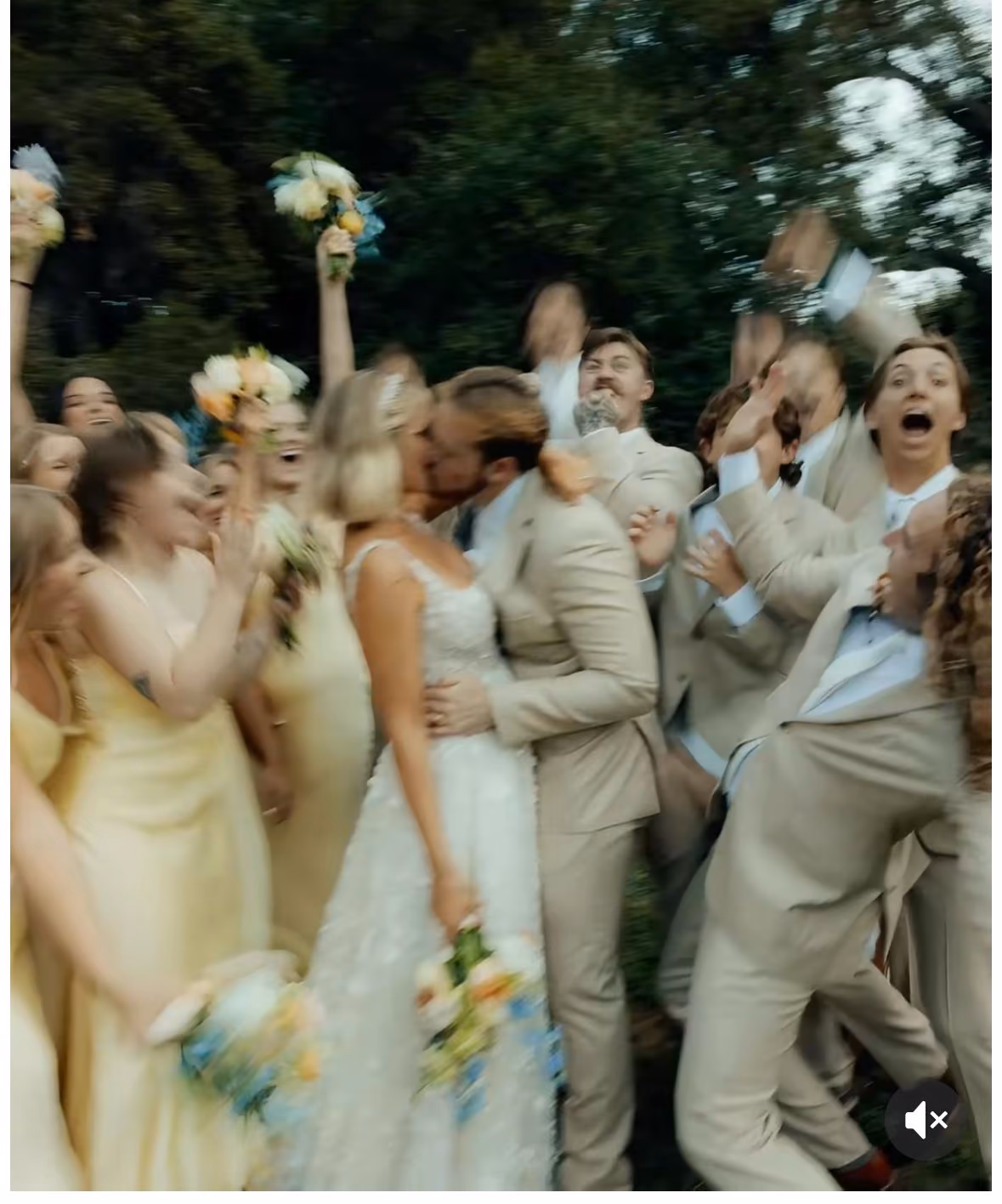 Bride and groom kissing amid a cheering bridal party